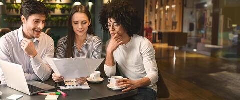Millennial business team discussing project in cafe, reading contract terms and conditions during business lunch, free space photo
