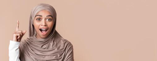 Eureka. Excited Black Girl In Hijab Having Idea, Pointing Finger Up, Got Problem Solution, Yellow Background With Free Space, Closeup photo