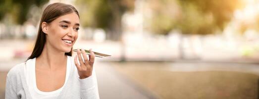 Modern technologies. Woman using digital voice assistant on cellphone outdoor, empty space photo