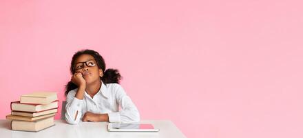 Bored Black School Girl Sitting Between Tablet Computer And Book Stack On Yellow Background In Studio. Boring Homework Concept photo
