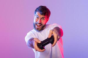 A man holds a game controller, his fingers pressing buttons and moving joysticks as he plays a game in neon light photo