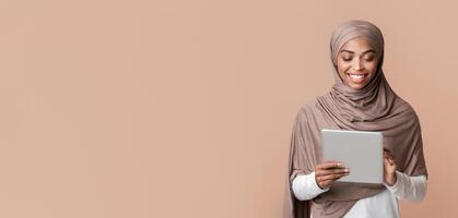 Cool App. Smiling Black Muslim Girl Using Digital Tablet, Browsing Internet Or Social Networks, Standing Over Yellow Background In Studio, Free Space photo