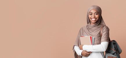 Education For Islamic People Concept. Portrait Of Happy Afro Muslim Woman In Headscarf With Backpack And Notepads Over Yellow Background, Copy Space photo