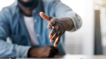 You're hired. Smiling black HR manager extending hand for handshake after successful job interview, selective focus on arm. photo