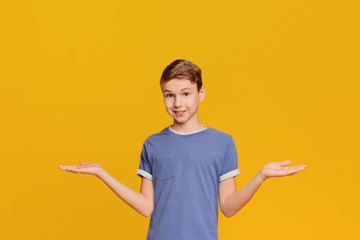 Cute little boy with doubting expression, both palms facing up, orange background with empty space photo