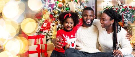 Christmas eve. Portrait of joyful afro family in interior decorated for Xmas, smiling and enjoying winter holidays together. photo
