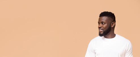 This image shows a smiling Black man wearing a plain white t-shirt. He is looking to the left, away from the camera, and his expression is friendly and approachable, copy space photo