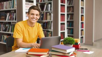 Intelligent guy studying in school library, using laptop and searching for information on internet, copy space photo