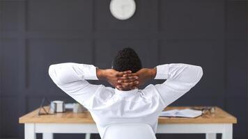 Back view of black employee relaxing in office, having break, copy space photo