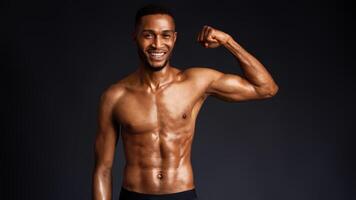 Athletic Man's Torso. Happy afro fitness model showing shoulder muscles, strong hands, chest and biceps over black wall photo