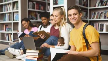 Group of mixed race classmates studying at library, sitting on floor with books and laptops photo