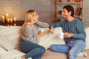 Happy Couple Spending Time Together Drinking Tea And Talking Sitting On Sofa At Home. Selective Focus photo
