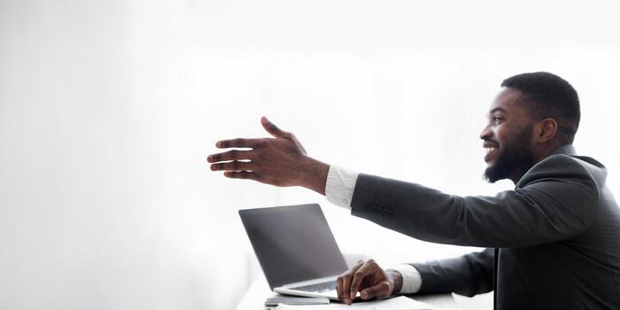 Friendly black HR manager extending hand for handshake after successful job interview, side view with copy space photo