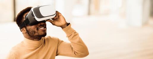 VR Technology. Black man wearing virtual reality glasses experiencing innovative technology, copy space photo