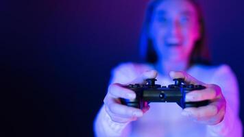 A woman is shown holding a game controller in her hands, her fingers positioned to press the buttons. The controller is connected to a gaming console or computer, copy space photo