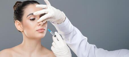 A woman is seated and receiving a cosmetic injection to her nose from a doctor wearing white gloves in a clinical environment. The procedure appears to be focused and meticulous, copy space photo