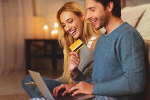 Online Shopping. Man And Woman Holding Laptop And Credit Card Purchasing Stuff On Internet Indoor. Selective Focus photo