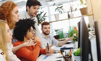 Discussing business strategy. Young millennial team working with new project, editing it on computer screen, free space photo
