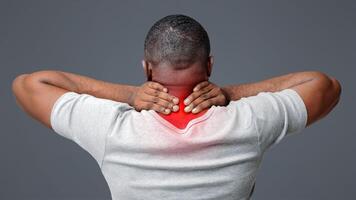 Afro guy suffering from pain in neck. Symptom of cervical chondrosis. Inflammation of vertebra, rear view photo