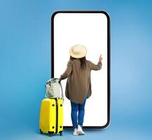 Black View Of Black Lady Using Big Smartphone Buying Travel Tickets Online Standing Near Huge Phone And Touching Blank Touchscreen On Blue Studio Background. Full Length, Square photo