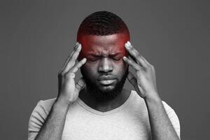 Young afro man having headache, touching his highlighted temples, migraine concept photo
