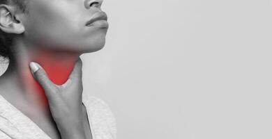 Monochrome photo of african woman suffering from tonsillitis, touching her highlighted with red throat, cropped, free space