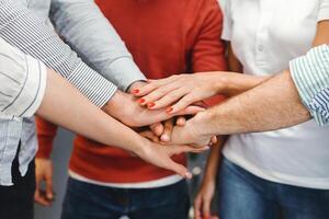 Cropped of diverse group of individuals of different ages and ethnicities coming together in unity and solidarity. They are standing in a circle, each extending their hands towards the center photo