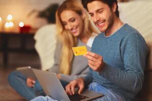 Husband And Wife Shopping Online Using Laptop And Credit Card Sitting On Sofa Indoor. E-Commerce Concept. Selective Focus photo