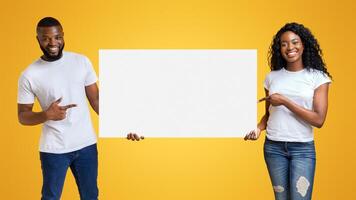 Black Smiling Man And Woman Pointing at White Blank Card With Empty Space photo