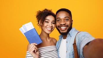 African American man and woman are standing together, holding a phone out in front of them to take a selfie. They are both smiling and posing for the camera, capturing a moment together. photo