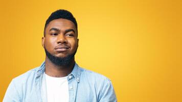 Portrait of african american man with sceptical face expression over yellow background with copy space photo