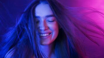 A young woman with a joyful expression on her face, smiling as her long hair blows in the wind, creating a dynamic and lively scene. photo