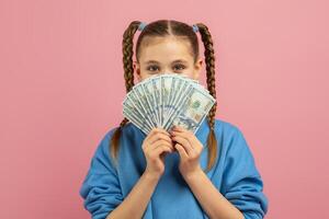 A young girl playfully covering her face with a handful of money, with a joyful expression. The money partially obstructs her smiling face while her eyes peek through. photo