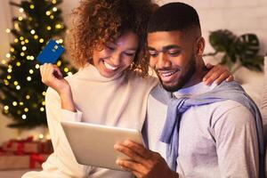 New year online shopping. Happy couple choosing gifts on tablet, enjoying evening at home photo