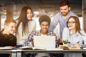 University students doing group project, using laptop and books in library photo