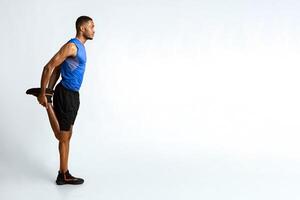 Warm Up. Side view of black man stretching legs before run over yellow studio wall, full length, copyspace photo