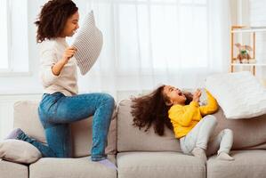 Jofyl Black Mother And Daughter Fighting With Pillows Laughing Having Fun Playing Together At Home. Selective Focus photo