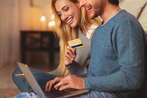 Online Shopping Concept. Couple Using Laptop And Credit Card Making Order Sitting On Floor At Home. Selective Focus photo