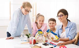 A teacher is helping her students build robots during a classroom activity. They are smiling and working together on the project. Positive and engaging learning environment for STEM education. photo