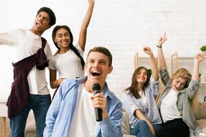 A diverse group of friends are gathered together, singing into a microphone. Each person is passionately expressing themselves through their voices photo