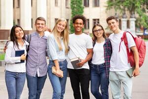Diverse students in campus, posing in front of university and looking at camera photo