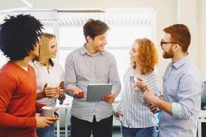 A diverse group of individuals, both men and women, standing in a circle facing each other. They appear engaged in conversation or discussion, displaying various gestures and expressions photo