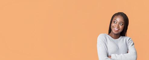 Beautiful black lady looking with interest at copy space over beige background, attracted with exciting info, panorama photo