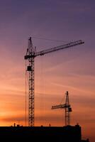 Shadows of two construction cranes on a sunset background. photo