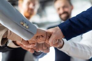Cropped of a business teams hands clasped together in a fist bump, showcasing their camaraderie and unity. The image captures the essence of teamwork and collaboration in a professional setting. photo
