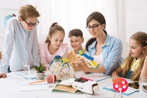 A group of young students are engaged in a STEM class, working together to build a robot. A teacher guides them, while they follow instructions and use their creativity to solve problems. photo