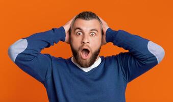 A man with a surprised expression on his face, his eyebrows raised and mouth slightly open in disbelief. His eyes are wide, showing shock and astonishment at whatever he is seeing or hearing. photo