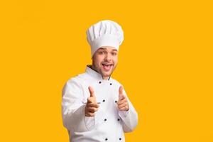 Hey, You. Smiling Chef Man Pointing Fingers At Camera Standing On Yellow Studio Background. Panorama photo