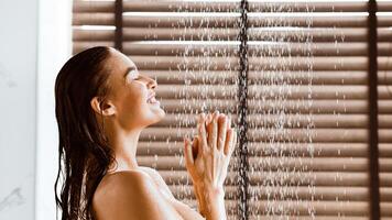 Woman Taking Shower Enjoying Water Splashing On Her, Side View photo