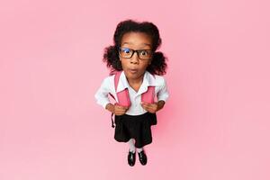Back To School Concept. Shocked Afro Girl Looking At Camera Posing In Studio. Yellow Background, High-Angle Shot photo
